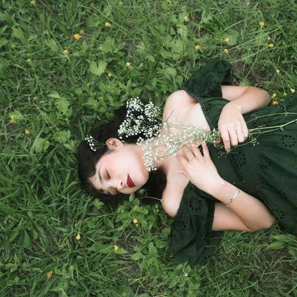 Woman in dark green dress lying in grassy field