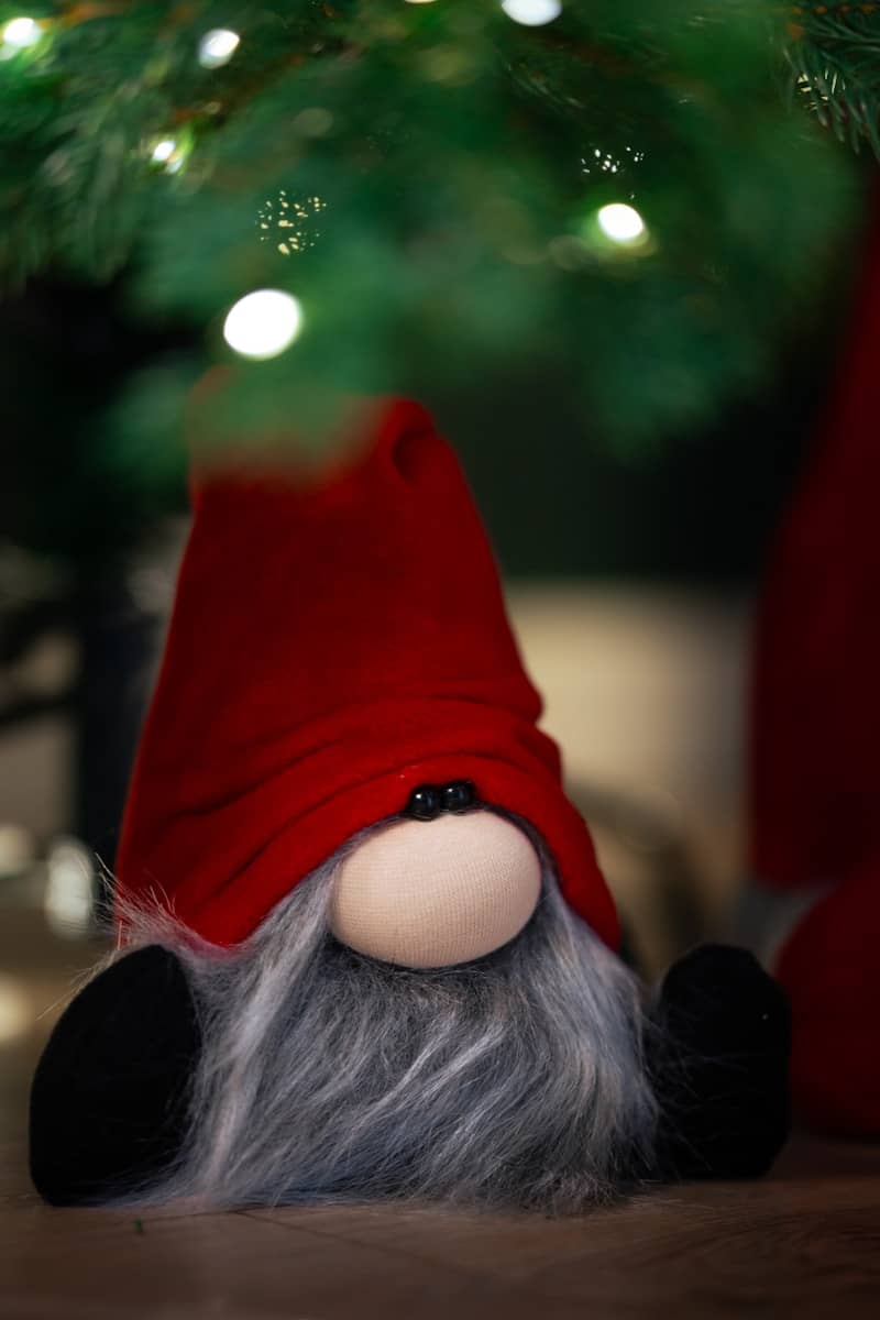 A red gnome doll laying under a christmas tree