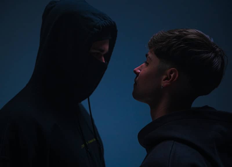 A man in a hoodie standing next to a man in a black hoodie