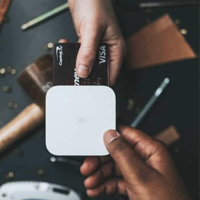person holding Visa card and white device