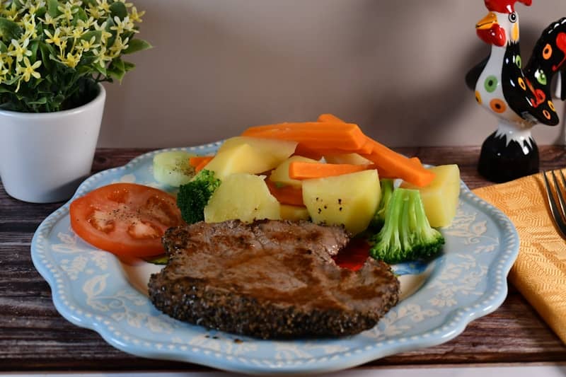 Steak with boiled potatoes, carrots, broccoli, and tomato