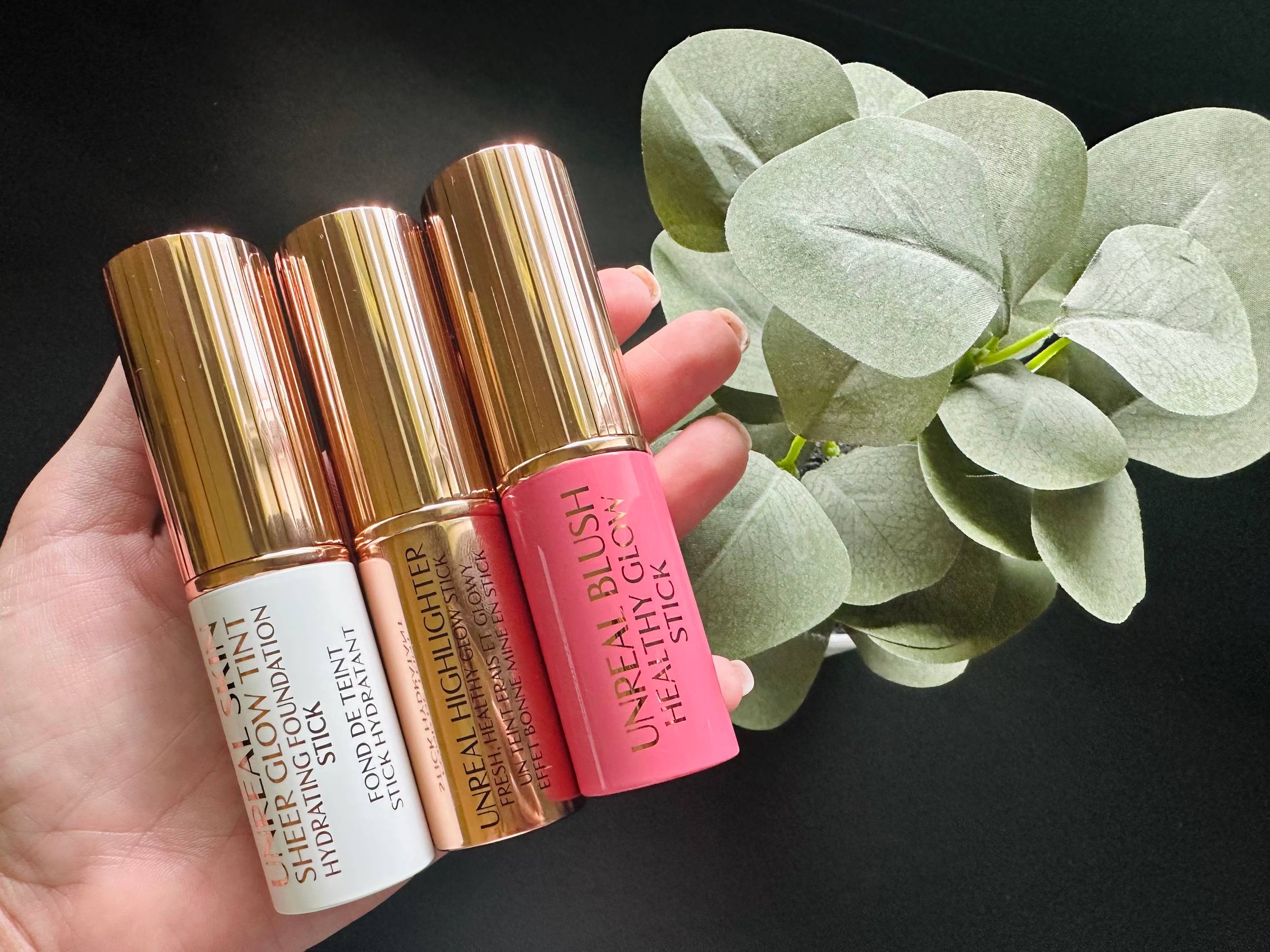 Hand holding three Charlotte Tilbury make up products