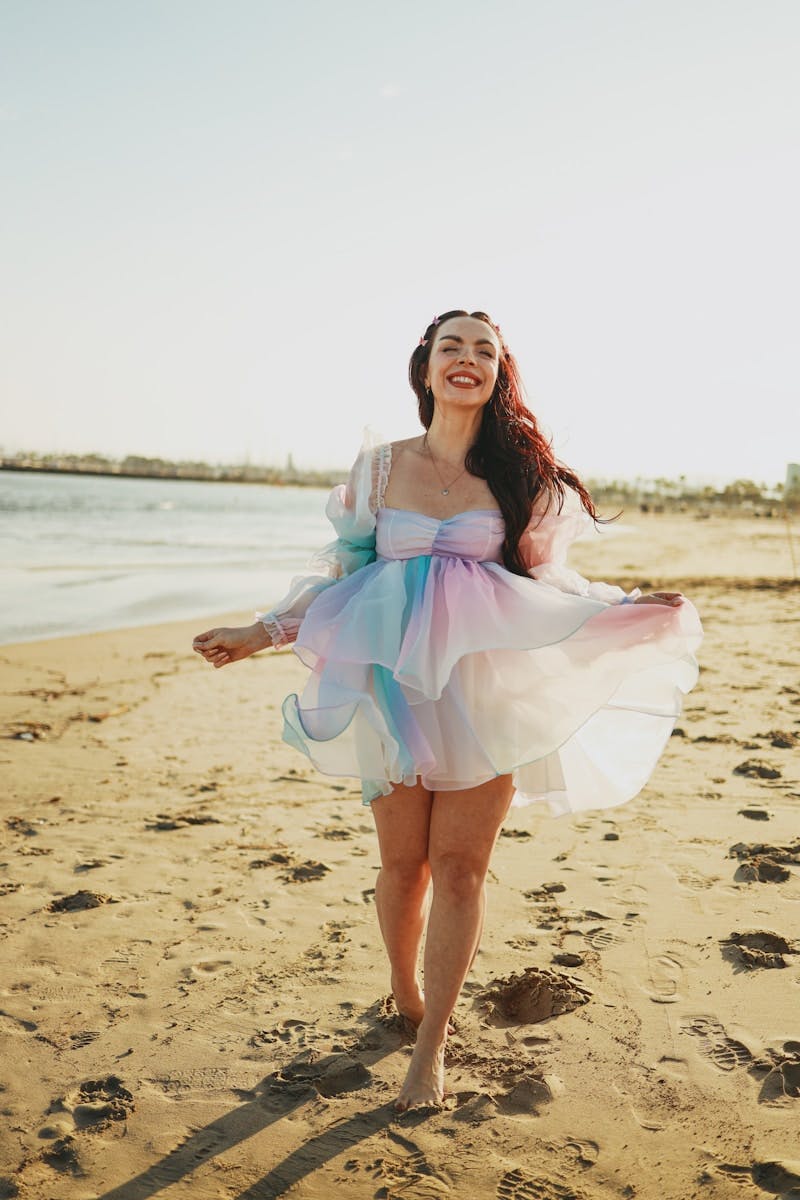a woman in a dress is walking on the beach
