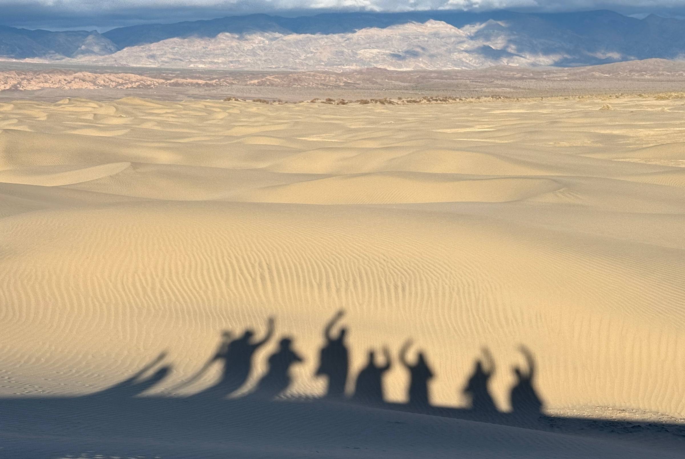 A group of silhouettes of photographers against the sand dunes.