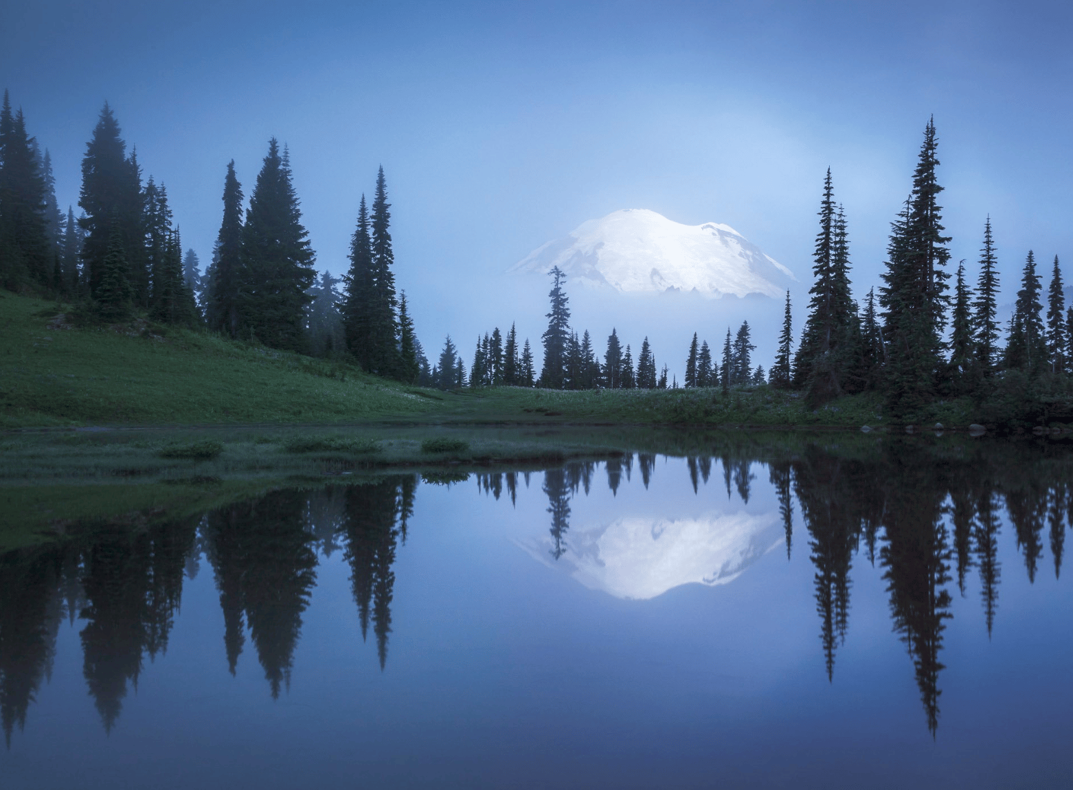 Mt. Rainier in the fog and clouds reflected in a pond. 