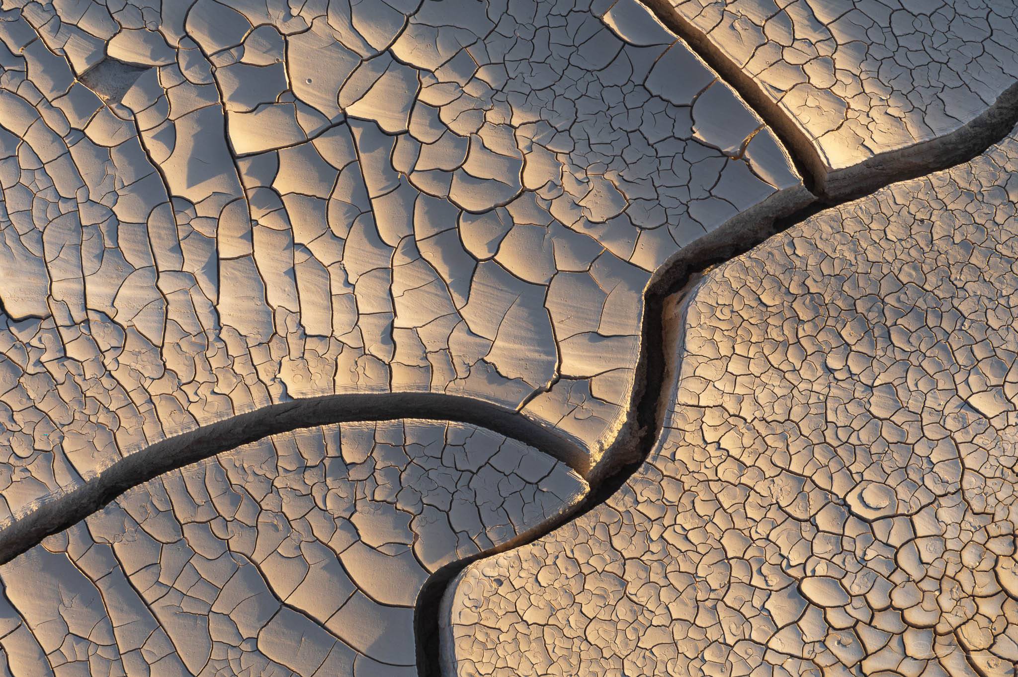 A close-up photo of the details of golden mud tiles with cracks and patterns. 