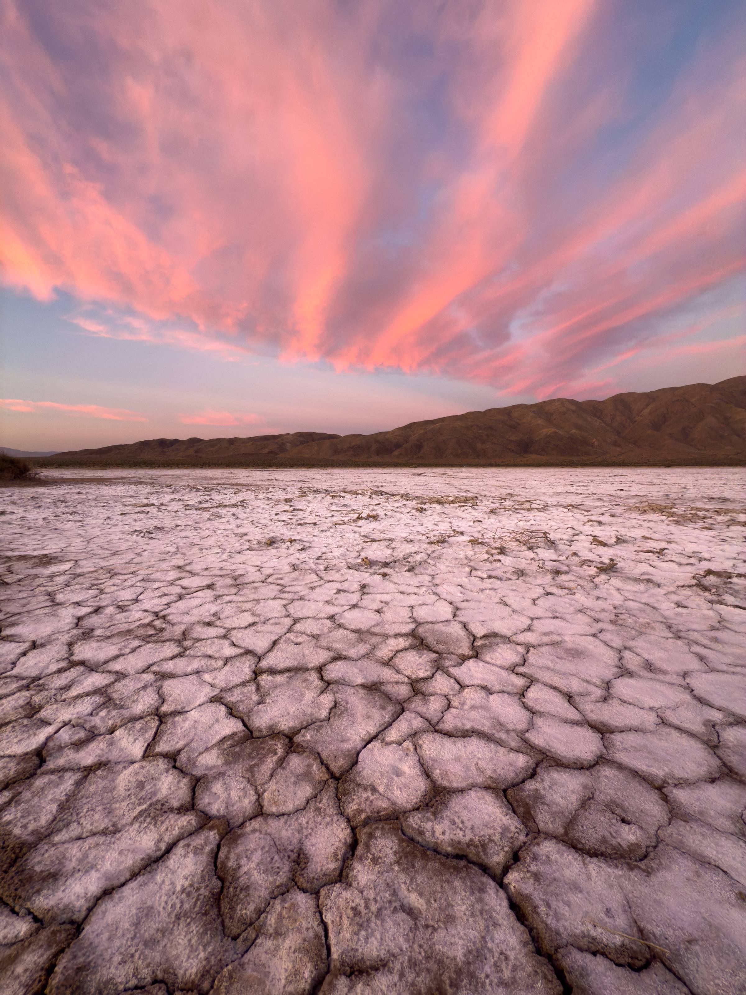 A sunrise pink sky stretches out over a dried mud playa.