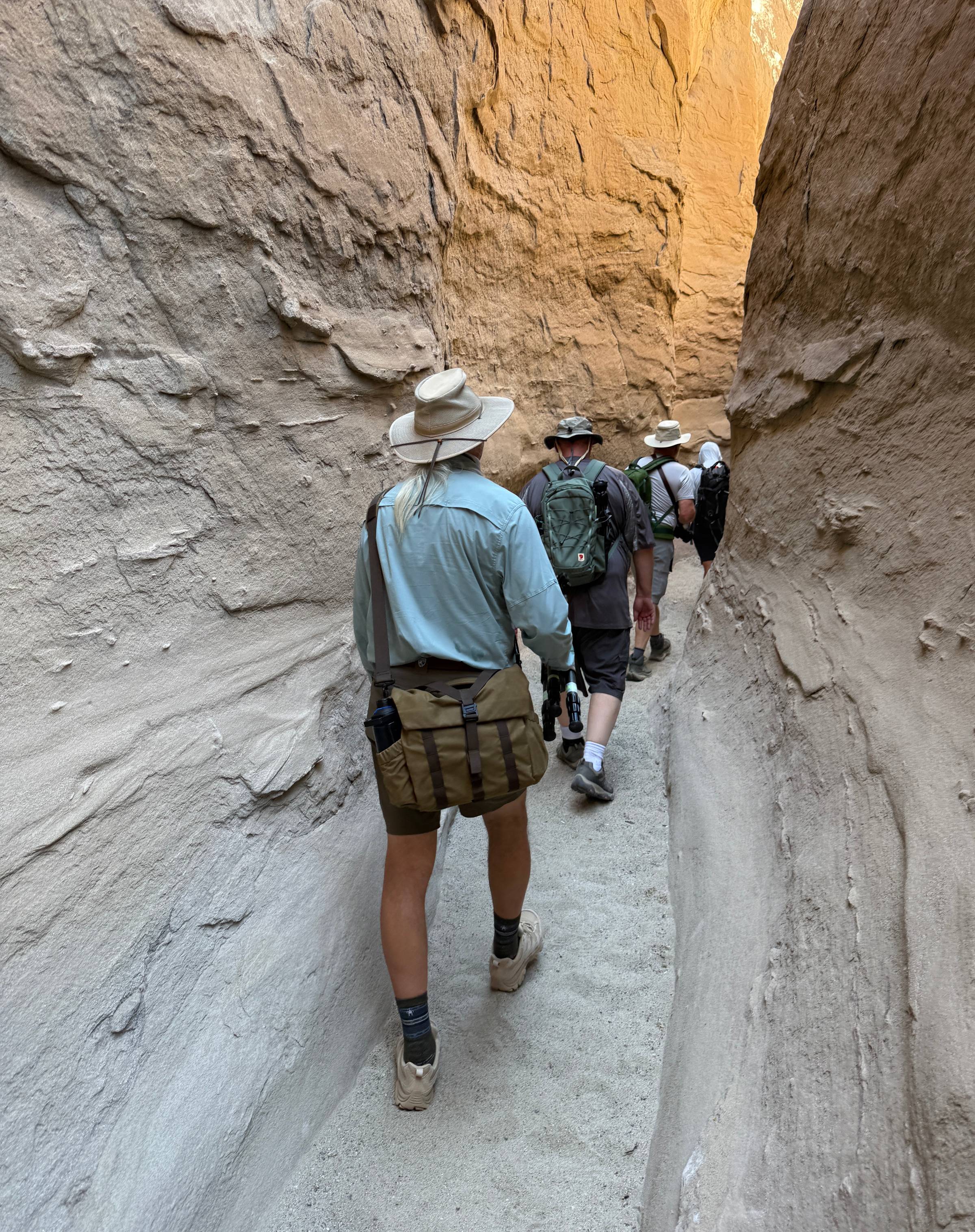 A group of hikers walk through a slot canyon.