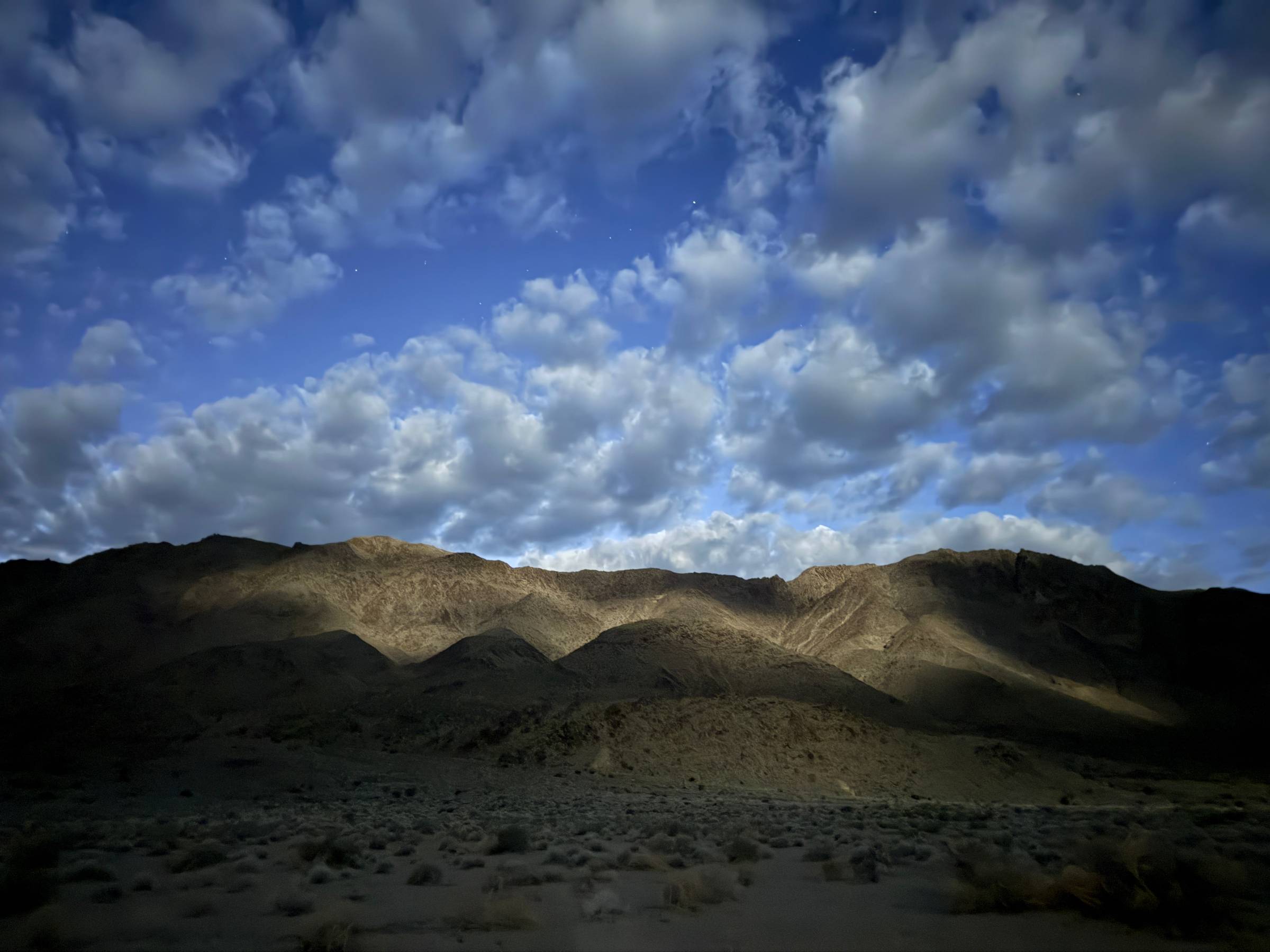 Dappled moonlight lights a mountain range at night.