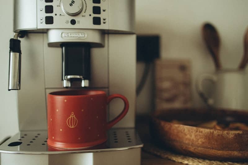 A red coffee cup sitting on top of a coffee maker