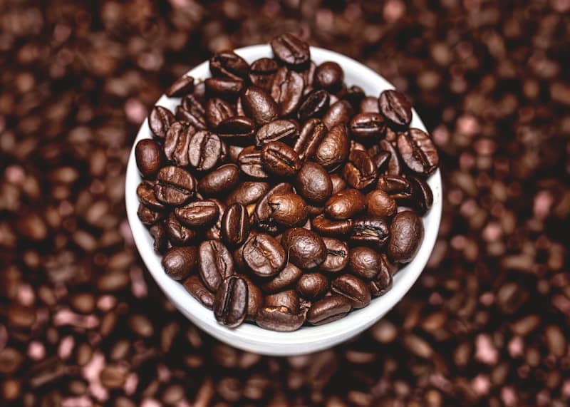 A white bowl filled with lots of coffee beans