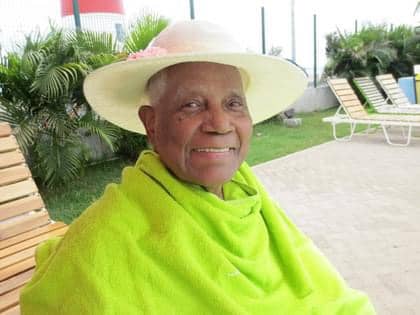 My dad in his older years by a pool wearing a bright green towel and my mom's hat.