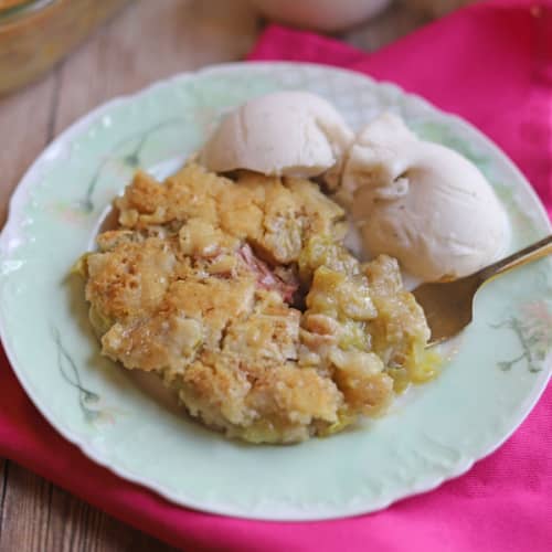 Magic rhubarb pudding cake with non-dairy ice cream on plate.