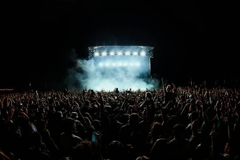 a large crowd of people in front of a stage with lights
