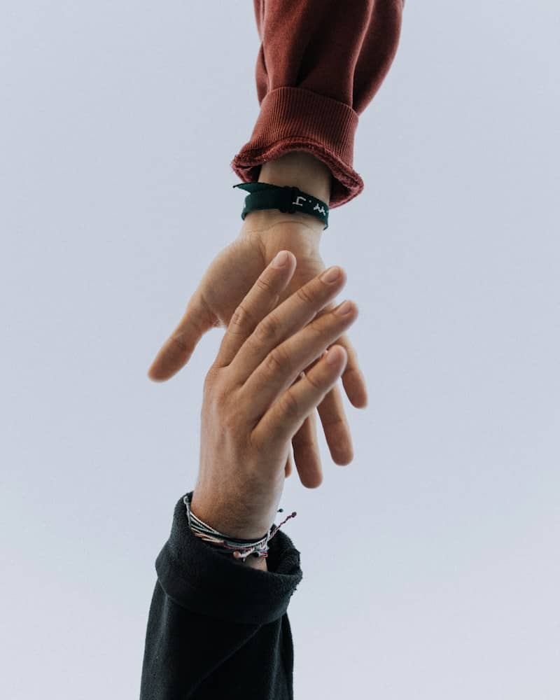 view of two persons hands reaching for each other