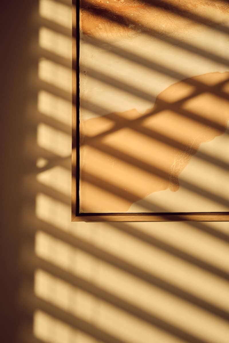 Sunlight casts striped shadows across a framed artwork.