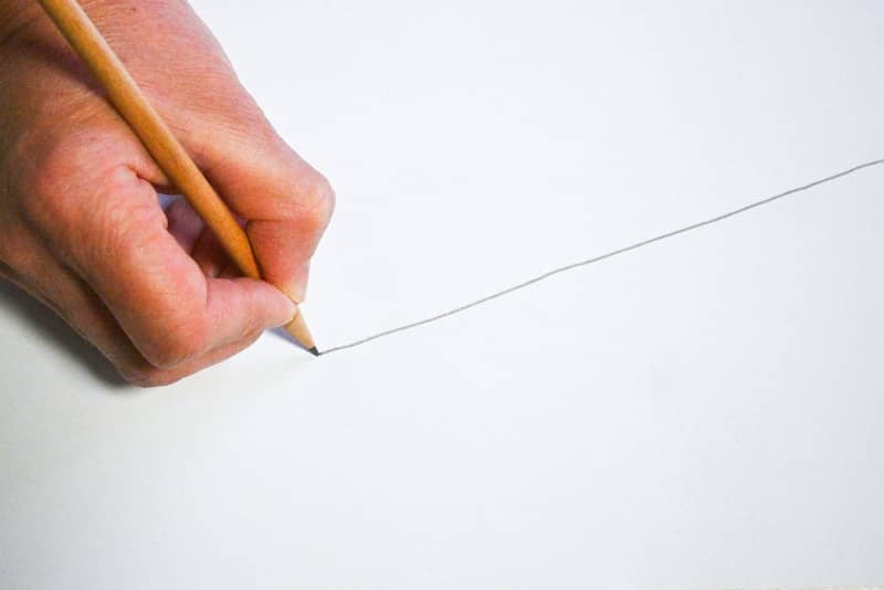 A person holding a pencil and writing on a piece of paper
