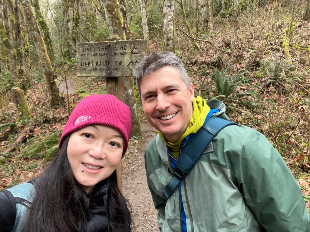 Angeline and husband in front of a trail sign, mid hike.