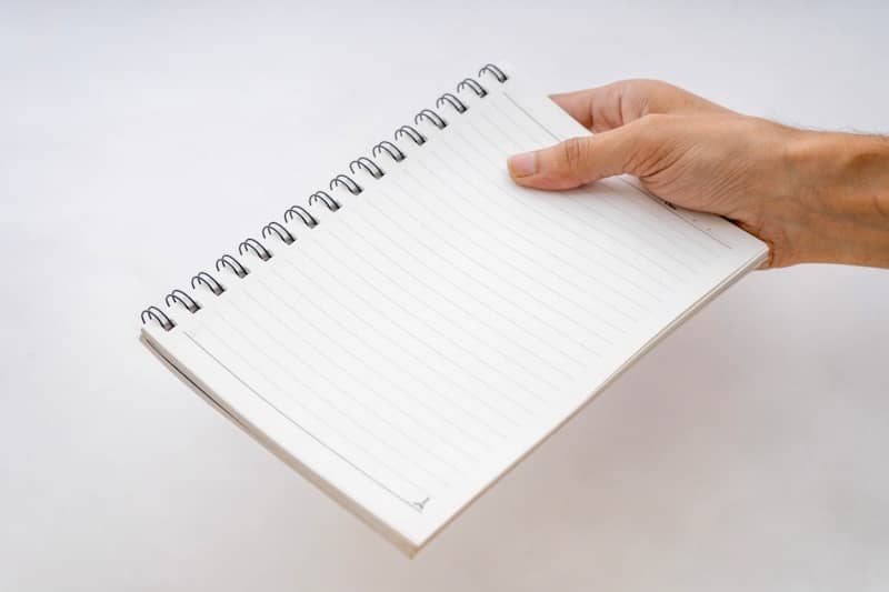 A hand holding a notebook with a spiral bound page