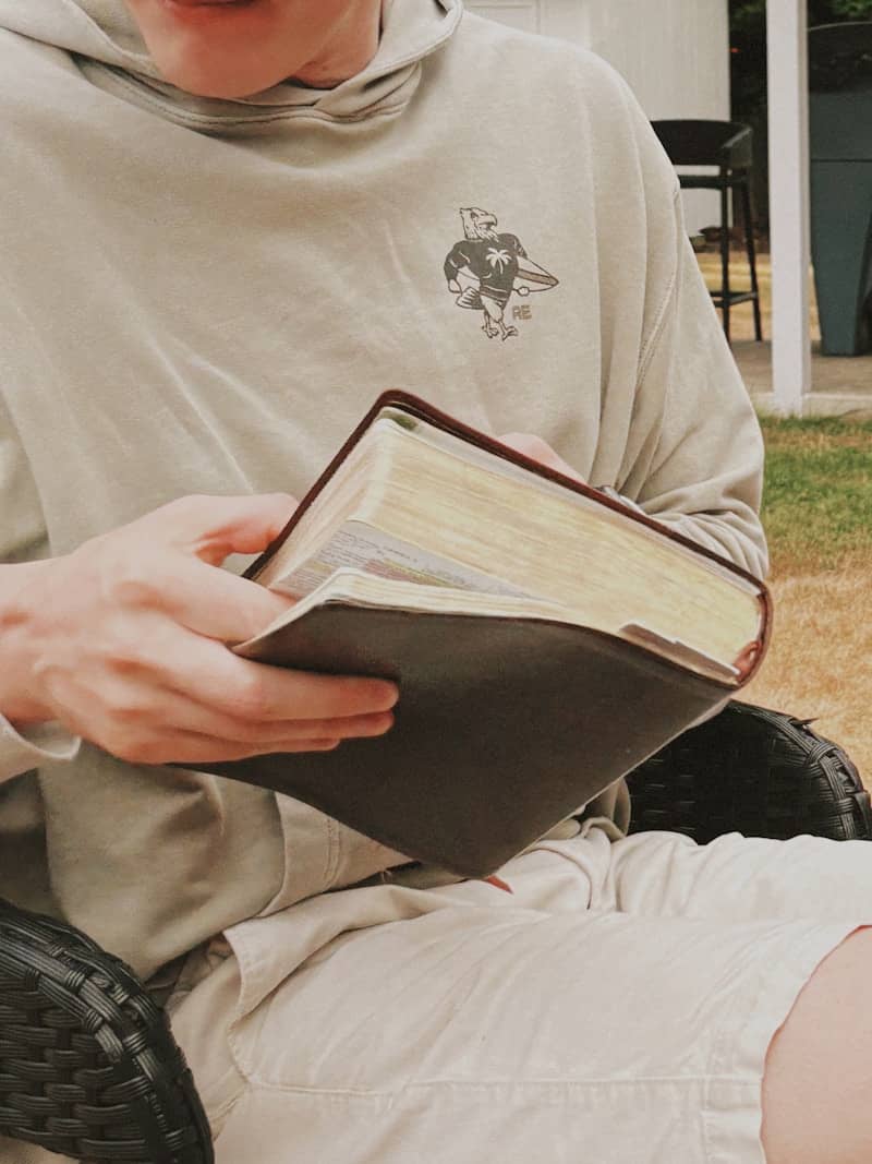 Person holding a large, open book outdoors