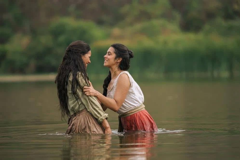 Dos mujeres vestidas con ropa de época se encuentran frente a frente en el agua, en una escena de la serie Mal de amores, basada en la novela de Ángeles Mastretta.