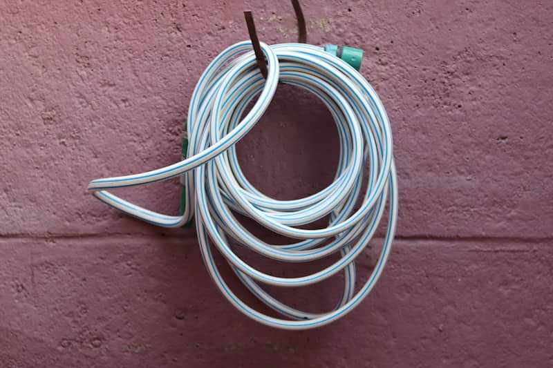 A white hose is coiled and hung on a wall.