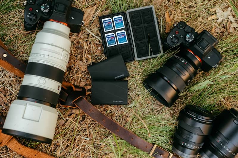 Two cameras with lenses and accessories on grass