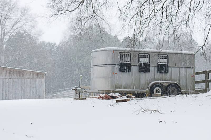 A horse trailer is parked in the snow