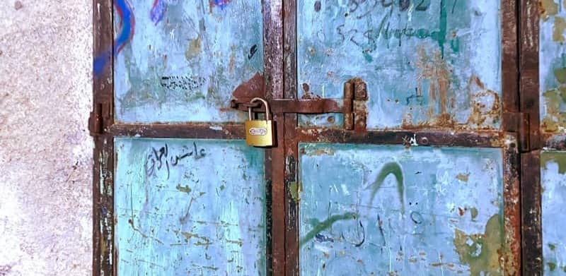 A weathered blue door with graffiti and a padlock.