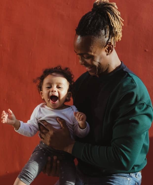 smiling man carrying child and playing