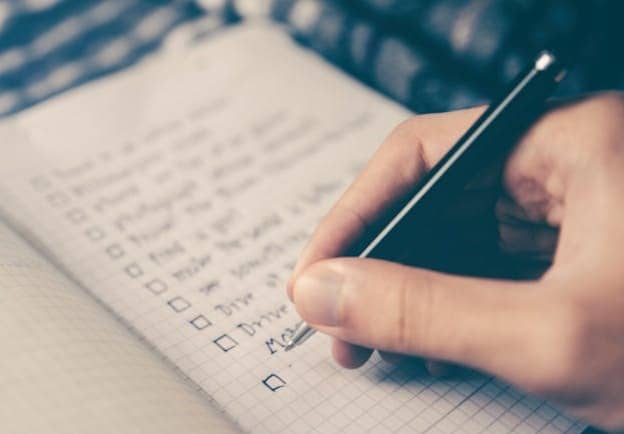 person writing bucket list on book