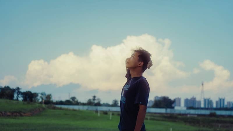 Young person looking up at fluffy clouds in sky