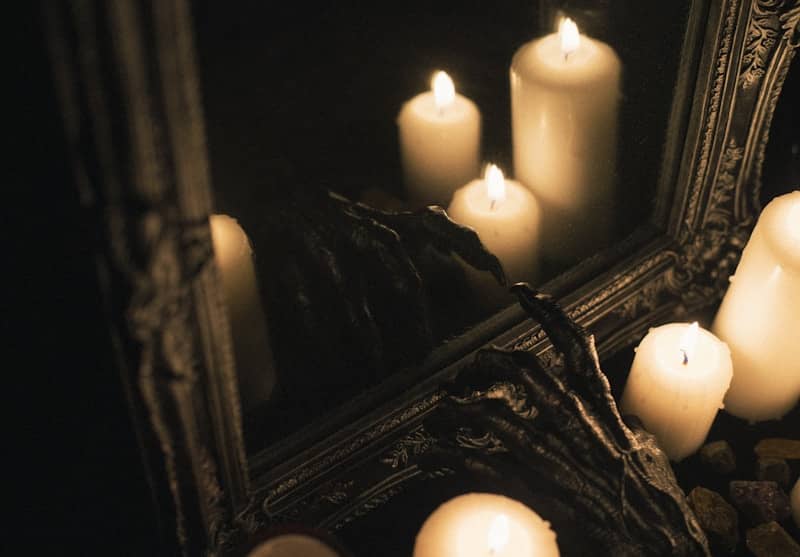 Candles are reflected in a dark-framed mirror.