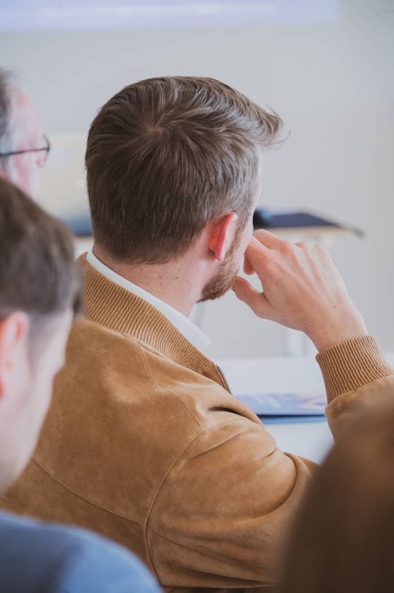 Man in a brown jacket at a meeting