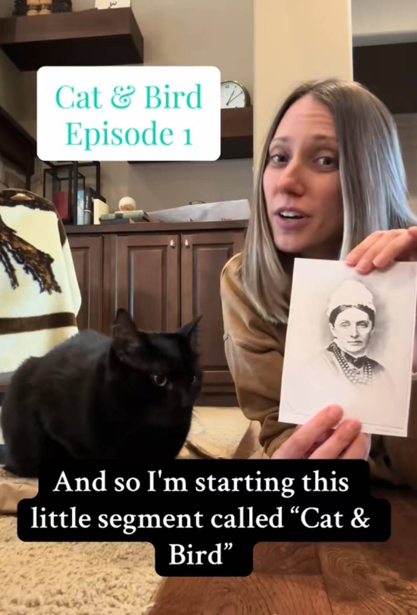 a photo of author casey cline holding a picture of Isabella Bird alongside her black cat