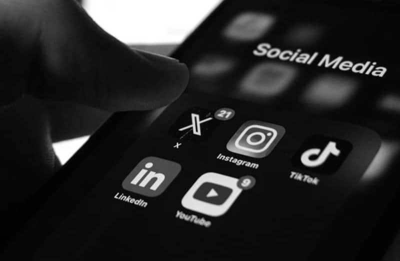 A person holding a smart phone with social media on the screen