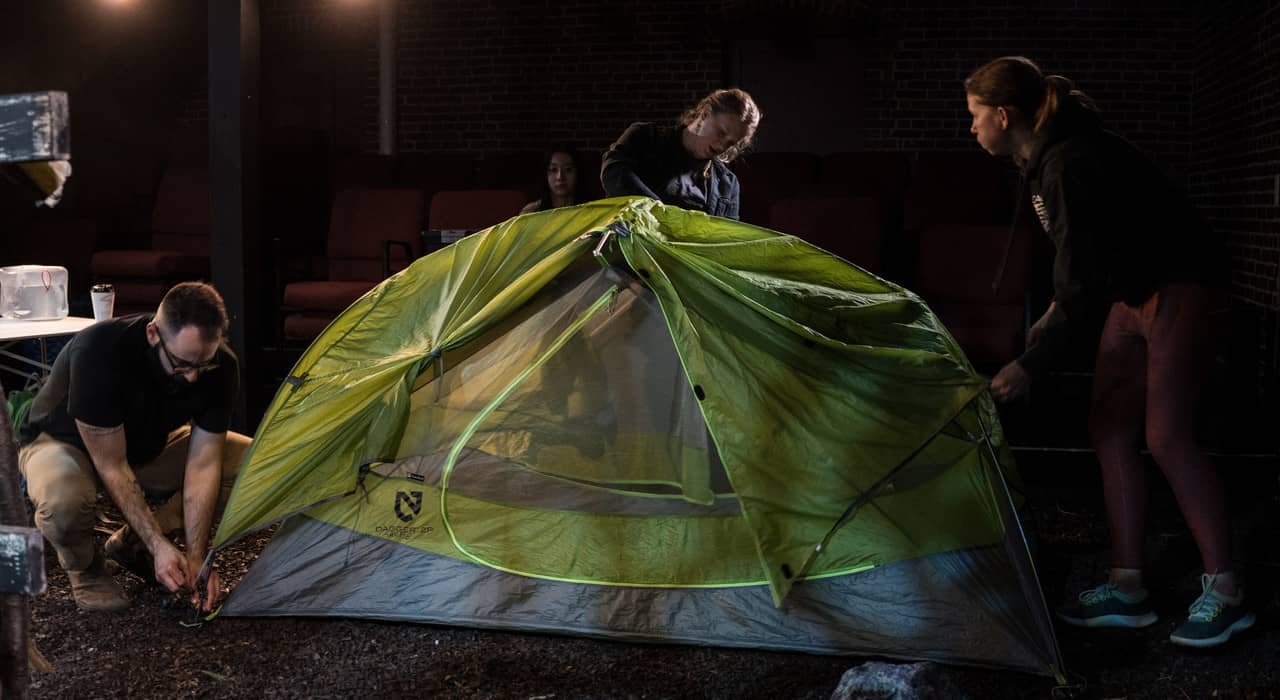 three people pitching a tent