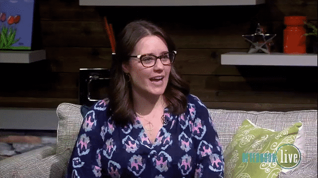 Clip of Maegan speaking on Afternoon Live, a local Portland, OR afternoon talk show. Maegan is wearing a dark blue patterned top and cat eye glasses, sitting on a gray sofa with green pillows.