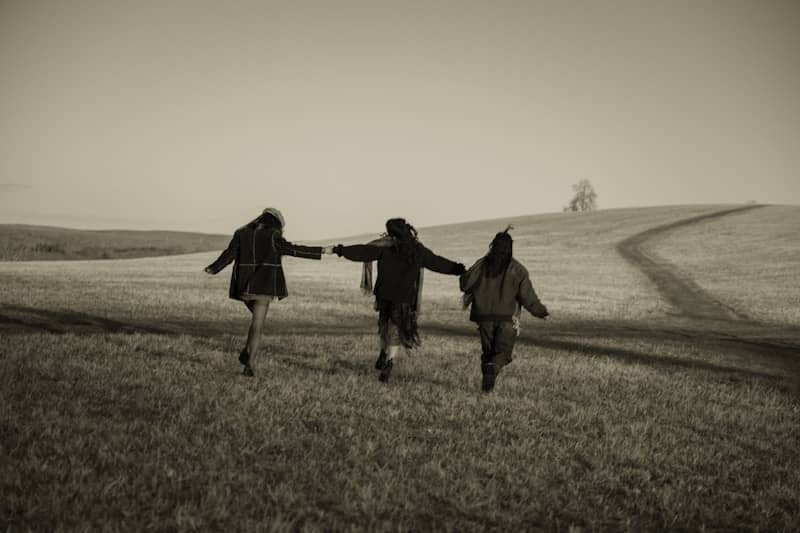 Three people running across a grassy field