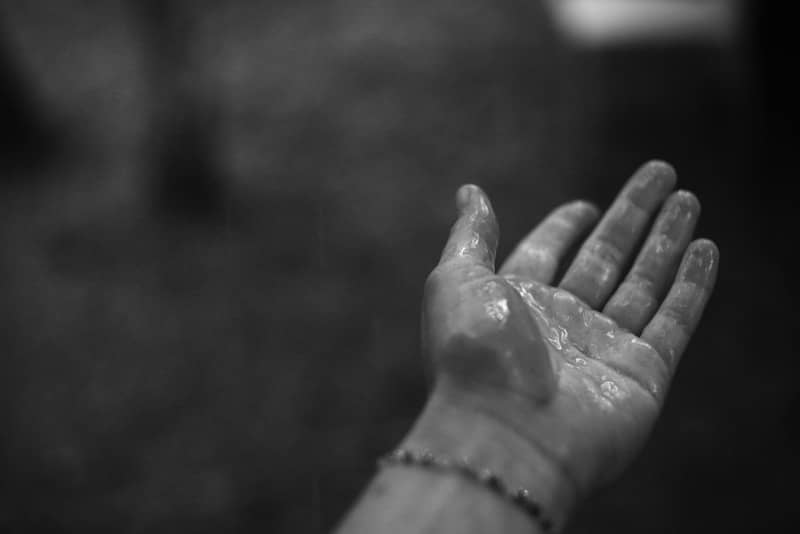 A wet hand with a beaded bracelet.