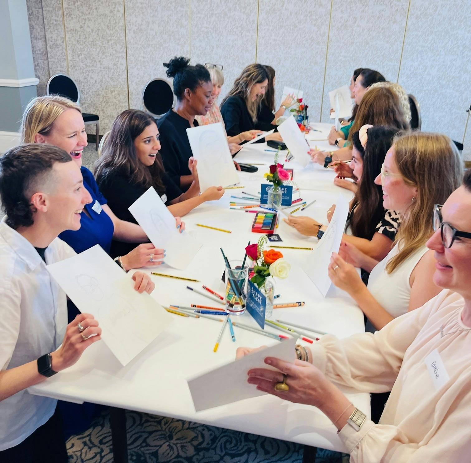 Group around collaborative art table smiling