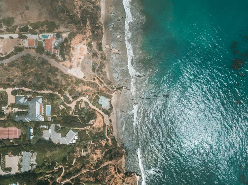 An aerial view of a beach with houses and a body of water