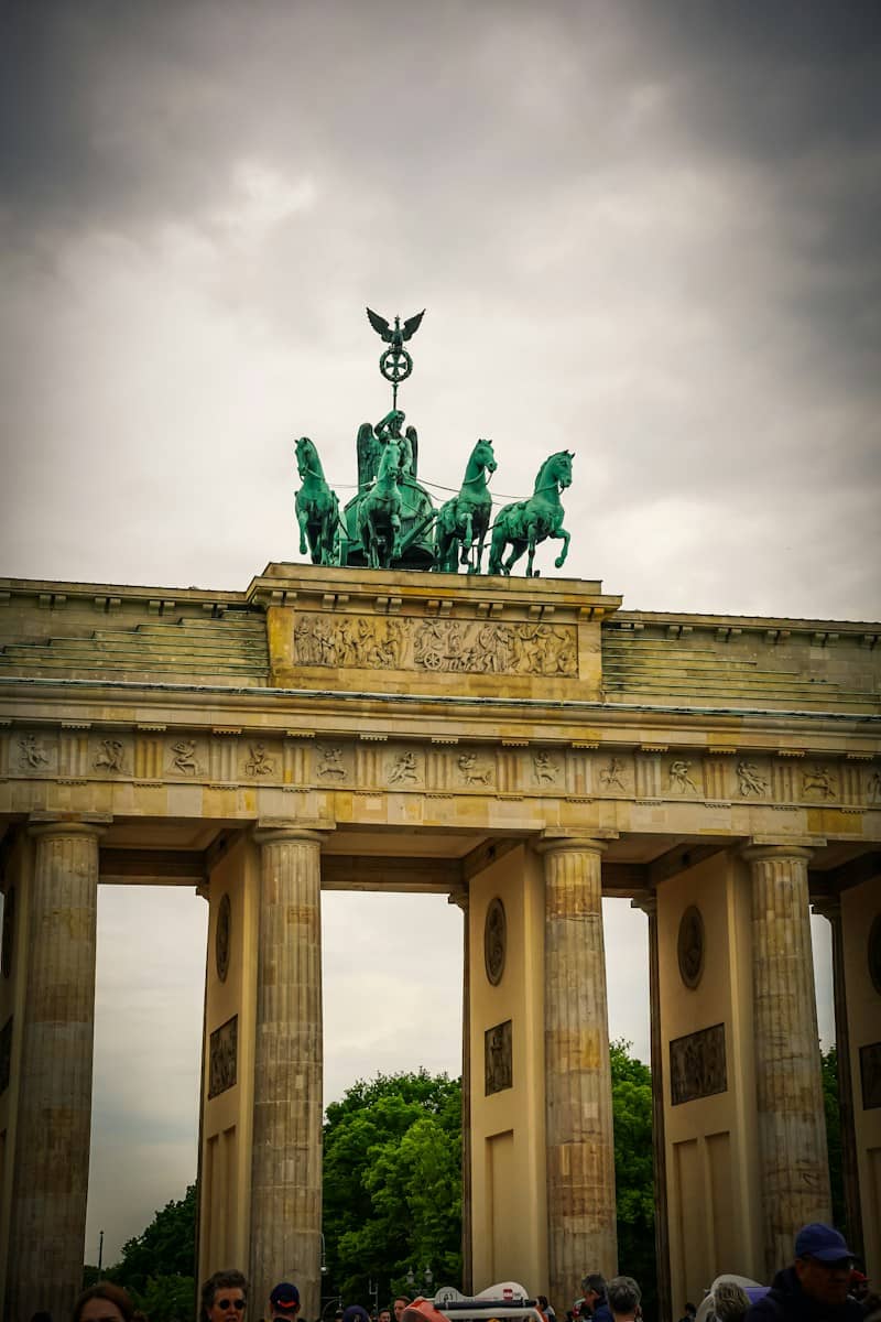 The Quadriga statue atop the Brandenburg Gate under a cloudy sky in Berlin