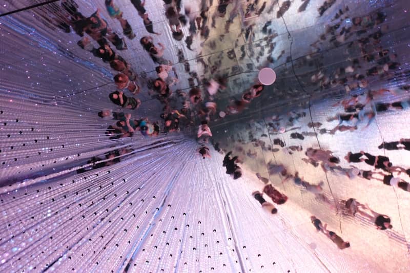 Overhead view of many people beneath a shimmering light installation.