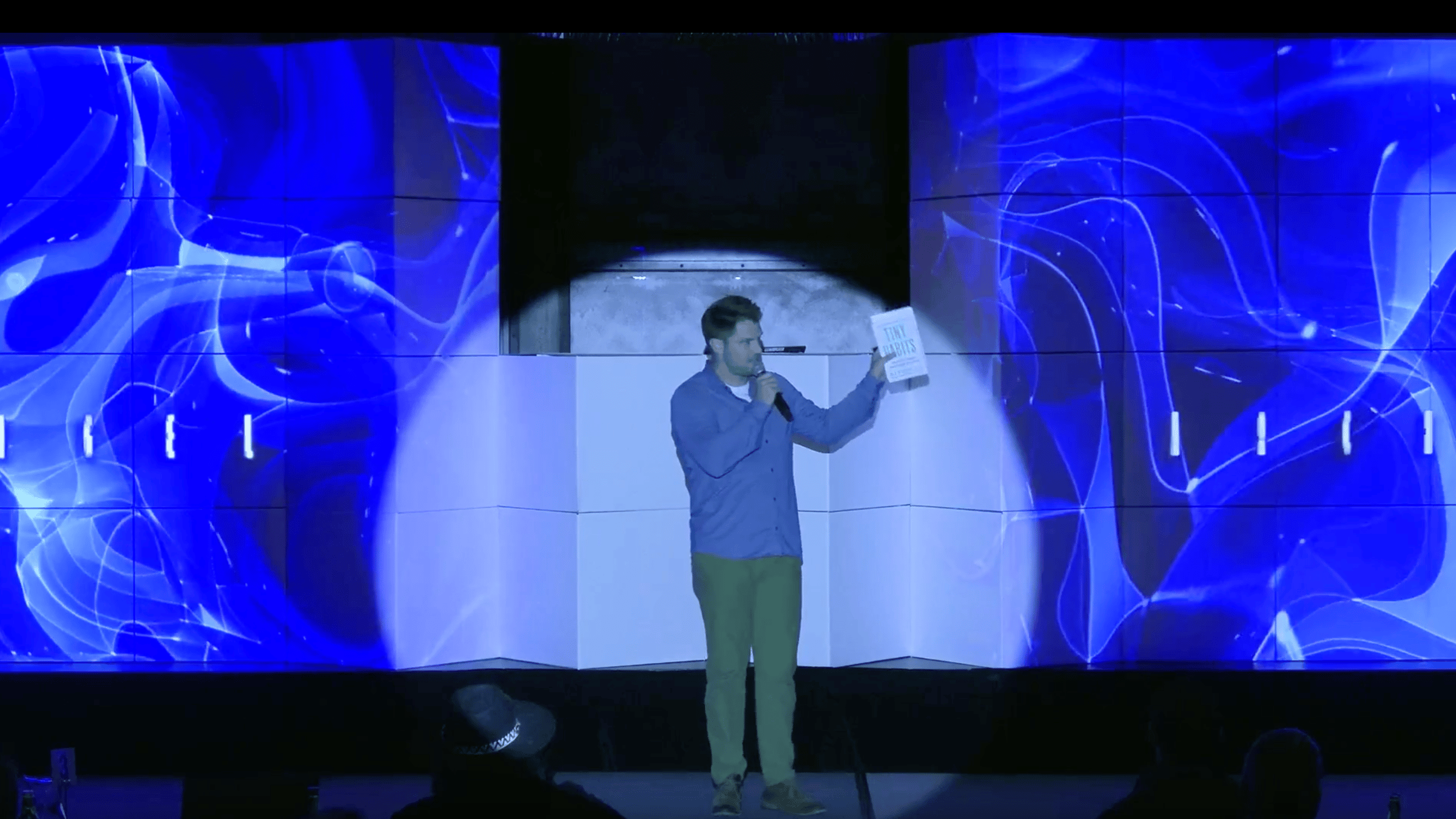 Charlie Hoehn holding Tiny Habits and Atomic Habits on stage