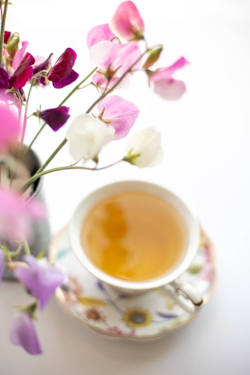 A cup of tea with sweet pea flowers