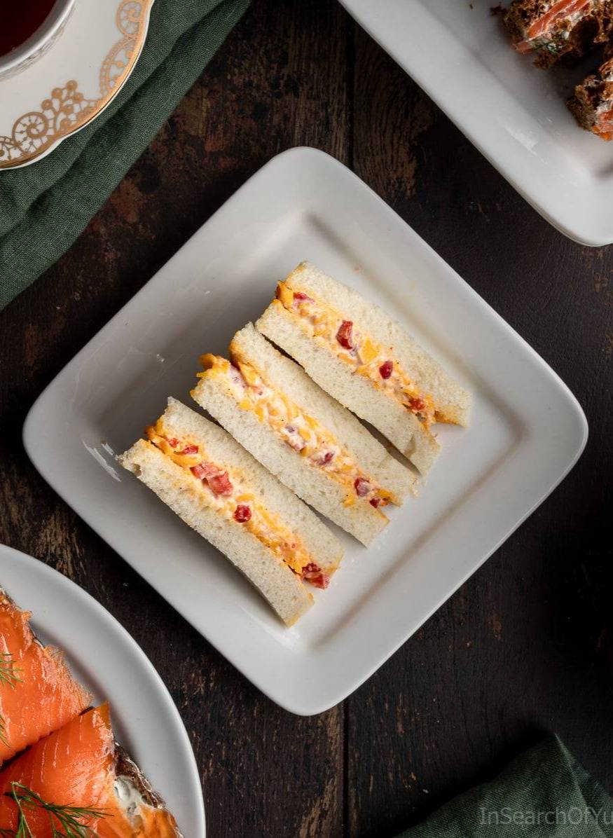 Three pimento cheese sandwiches on a white plate.