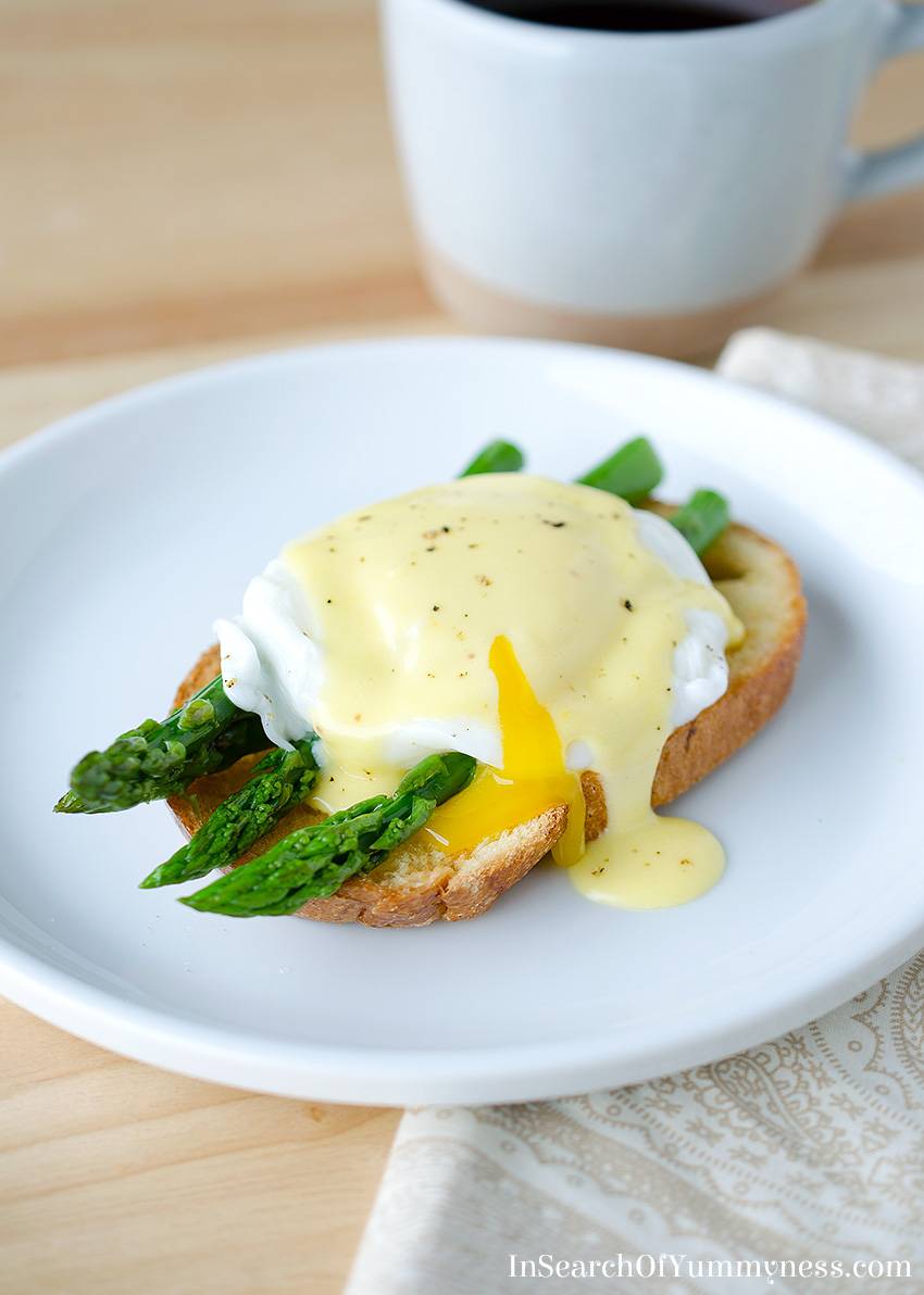 A plate with eggs benedict with asparagus.