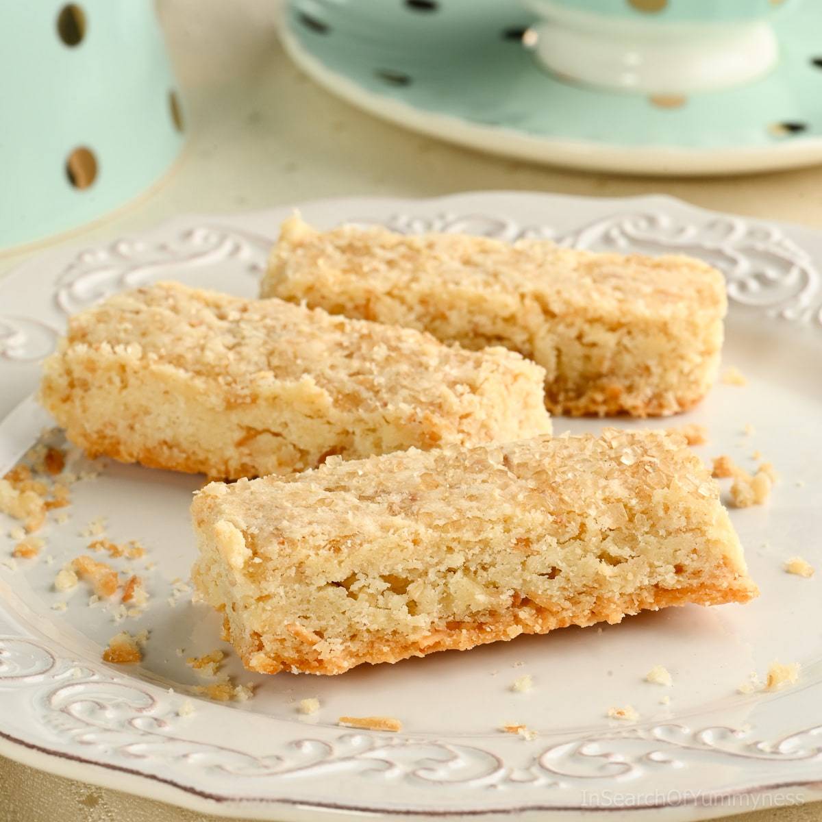 Three coconut shortbread cookies on a fancy white plate.