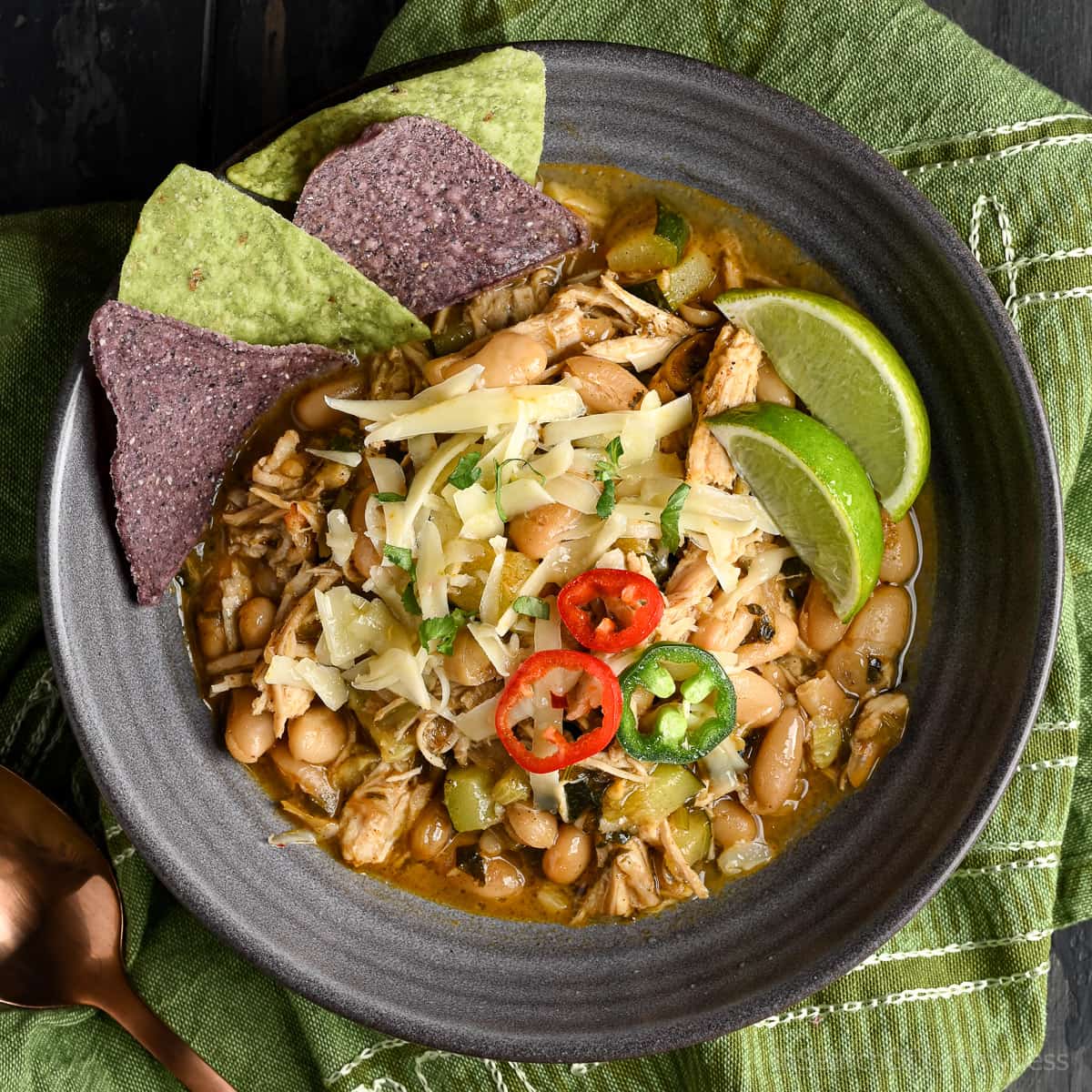 A bowl of white turkey chili with lots of fun toppings.
